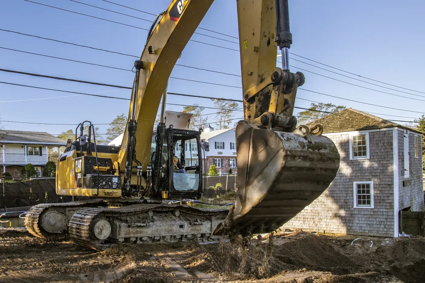 Tracked excavator loading soil with its bucket on a residential excavation site