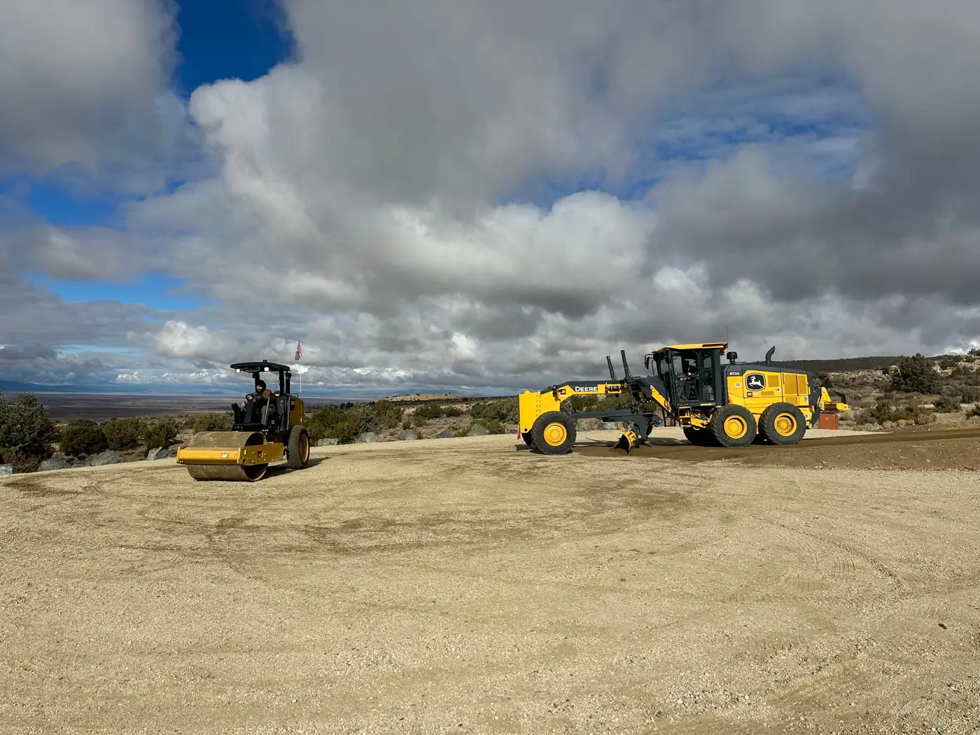 Motor grader and roller compacting a freshly graded gravel surface