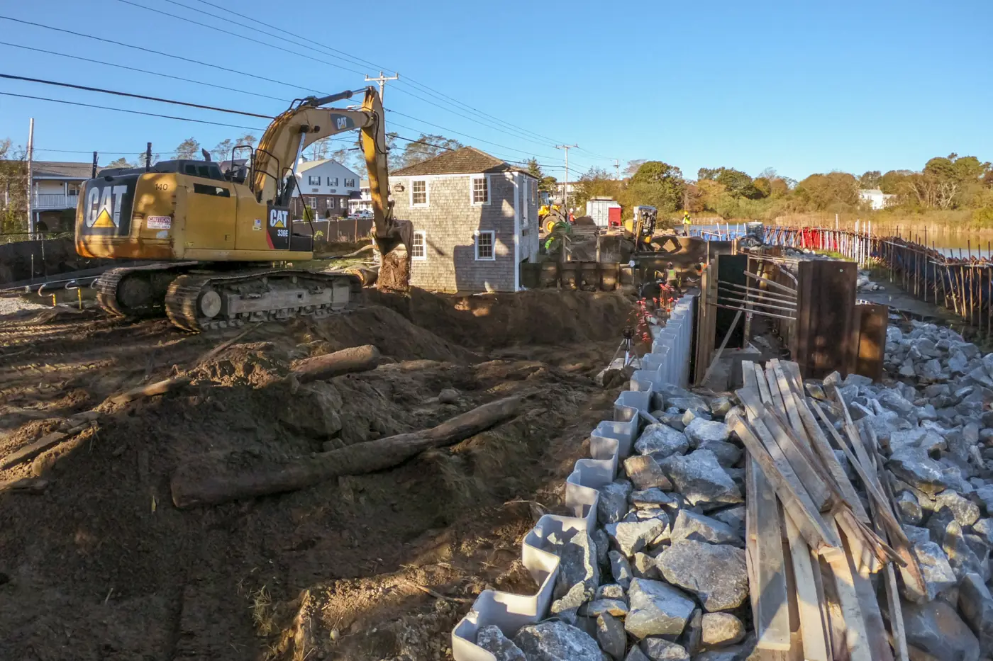 Excavator cutting and moving earth on a residential construction site near the water